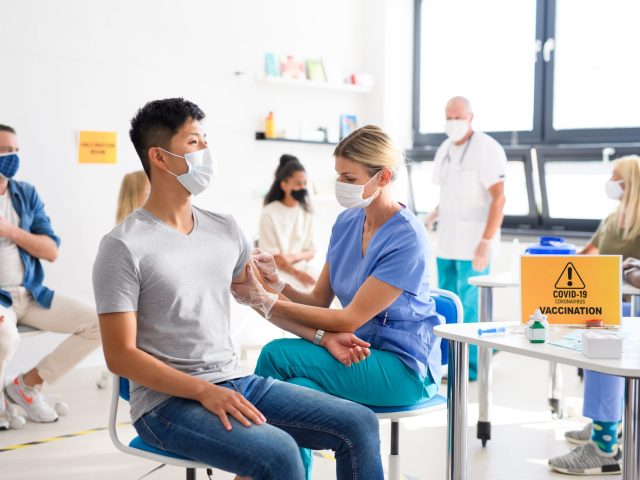 Man with face mask getting vaccinated for coronavirus, covid-19 Group of patients wearing masks getting COVID vaccine