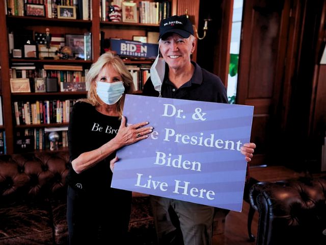 Dr. jill Biden and her husband, President Joe Biden holding a sign saying that they live here.
