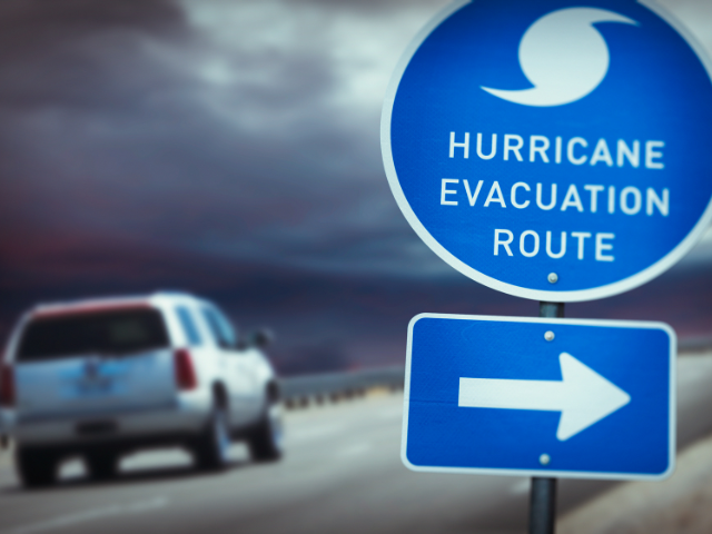 A vehicle is seen leaving on a two-lane road during hurricane season.