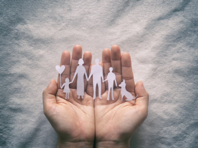 Imagery of a paper cut-out family being held in the palm of someone's hands as a representation related to Intimate partner violence