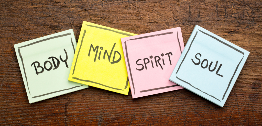 Four sticky notes are lined up next to each other with the four tenets of Holistic Nursing: body, mind, spirit, and soul.