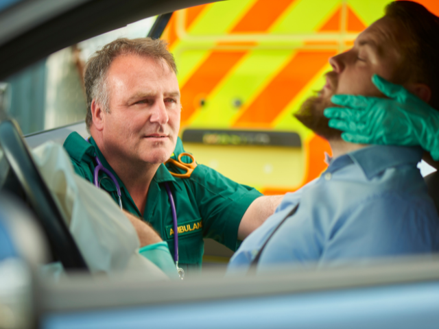 A paramedic assesses an injured patient who was in a car crash during mass casualty training.