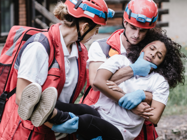 Two first responders carry an injured woman during mass casualty training.