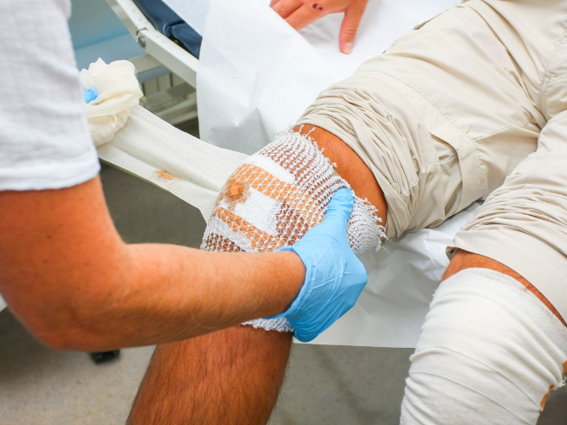 A medical professional wraps a medical bandage around a knee as part of pediatric wound care.
