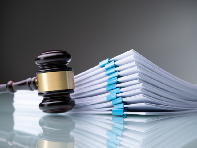 A stack of documents next to a gavel, representing what strike nurses would have filed.