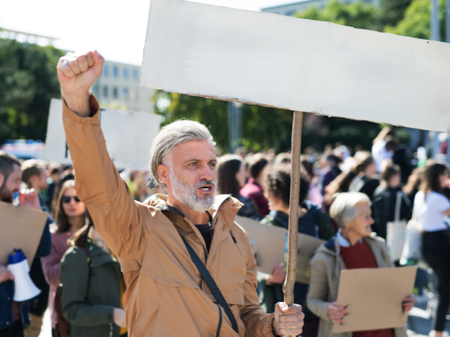 A man on strike holds a blank picket sign, similar to what strike nurses did