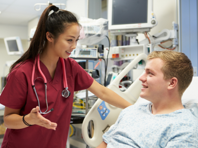 A nurse, who could have collective bargaining rights, speaks to a woman in a hospital bed.