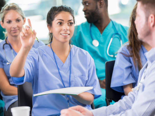 A nursing student, like those at Washington State University, raises her hand in a classroom setting.